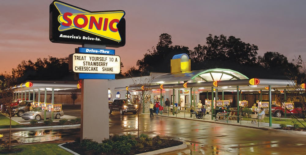 A Sonic location at night with a truck pulling up to Sonic's iconic call-box park and  order spot. 