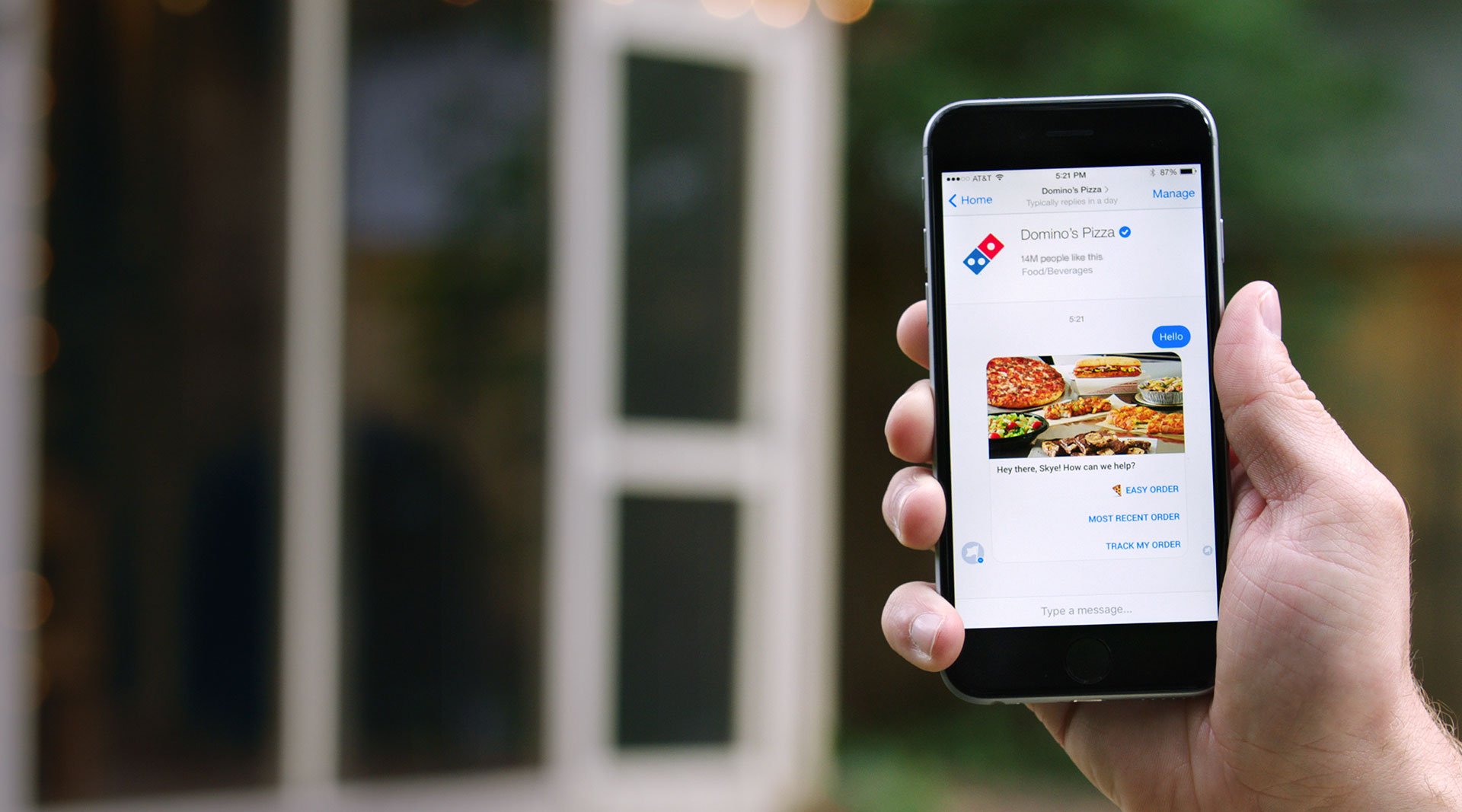 Hand holding a smartphone displaying ordering from Domino's via Facebook Messenger