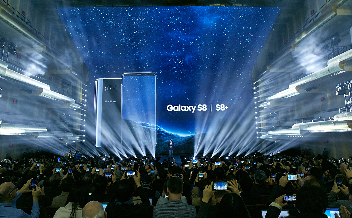 Galaxy S8 and S8+ projected on a large screen in front of a packed auditorium.