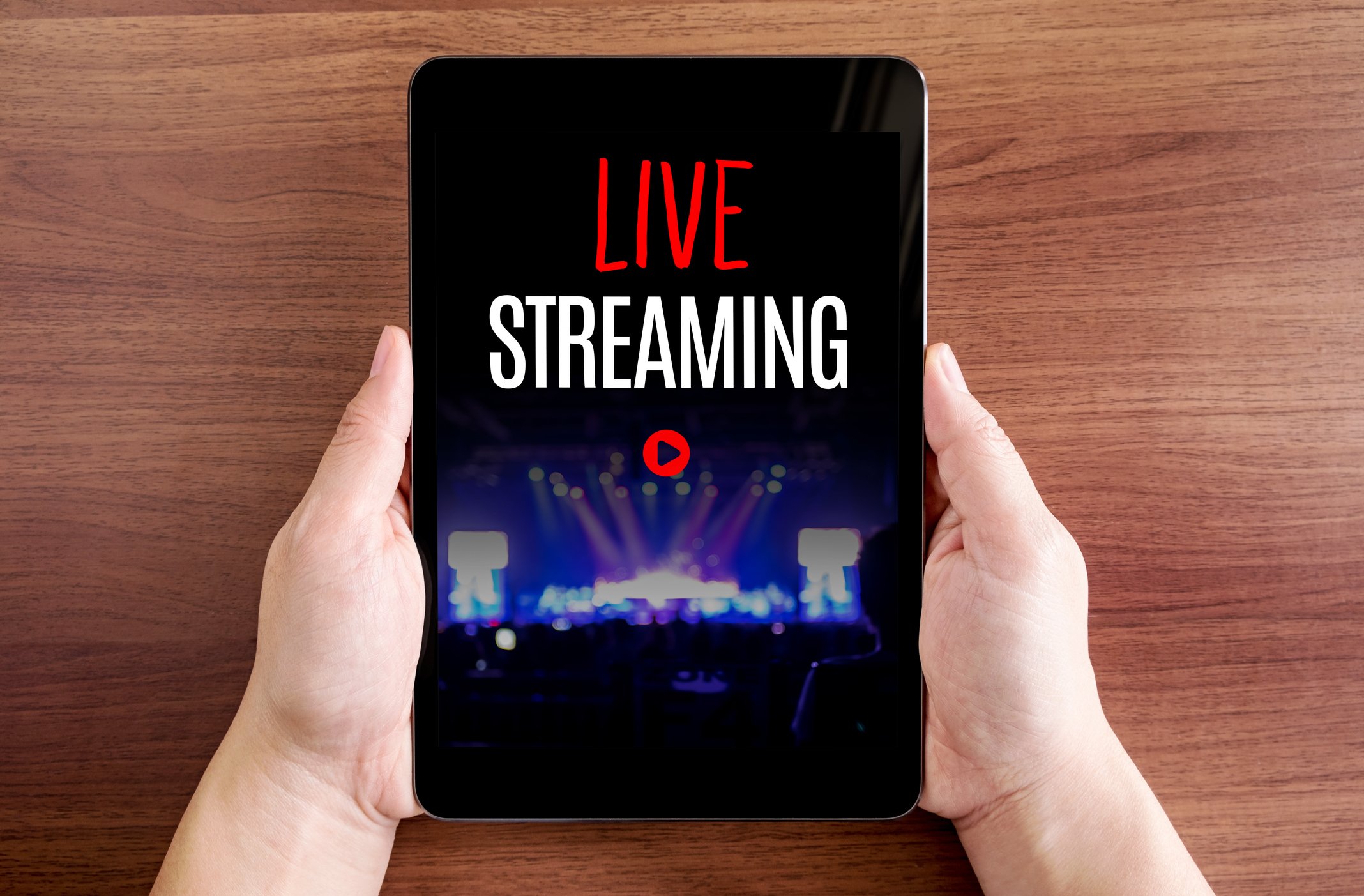 Two hands holding tablet with Live streaming and play icon