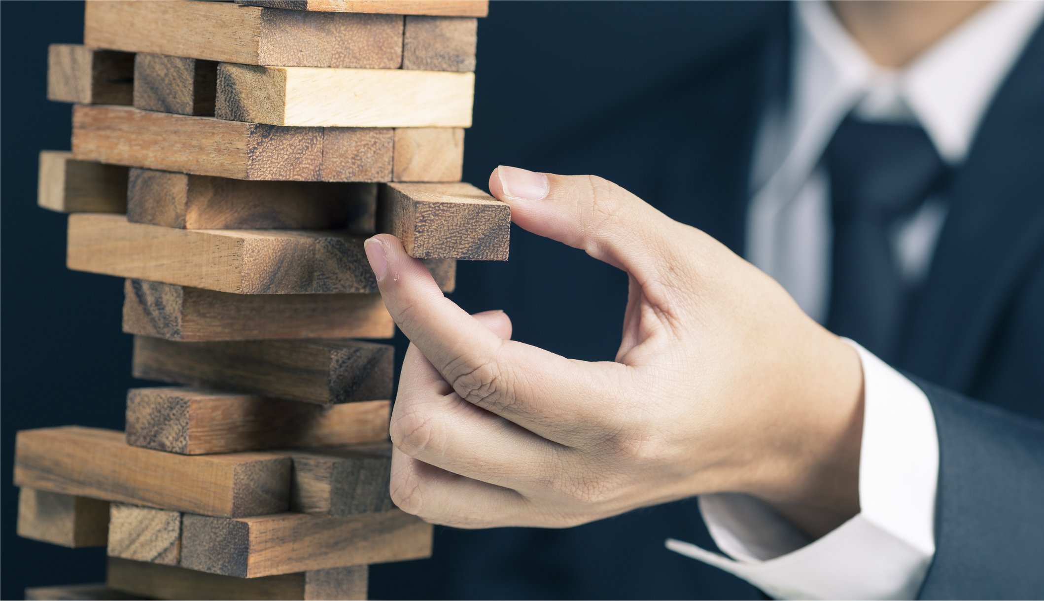 A businessman removes a Jenga block.