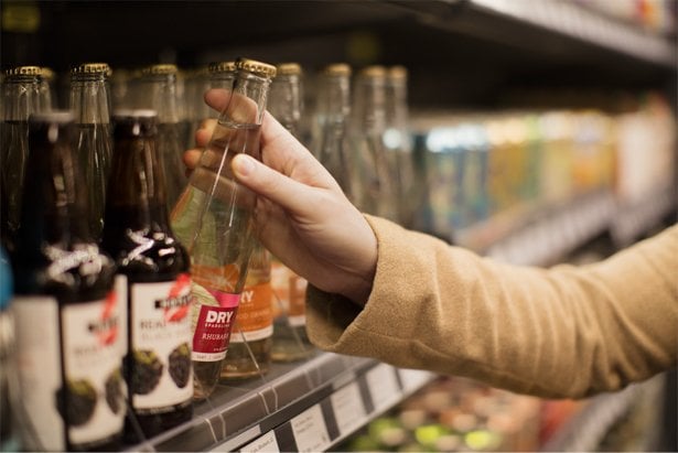 A person grabs a bottle off of a grocery shelf at an Amazon Go store in Seattle.