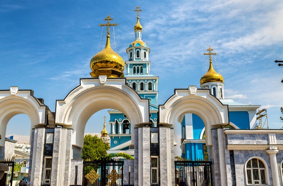 The gold domes of the Dormition Cathedral shine against a bright blue sky.