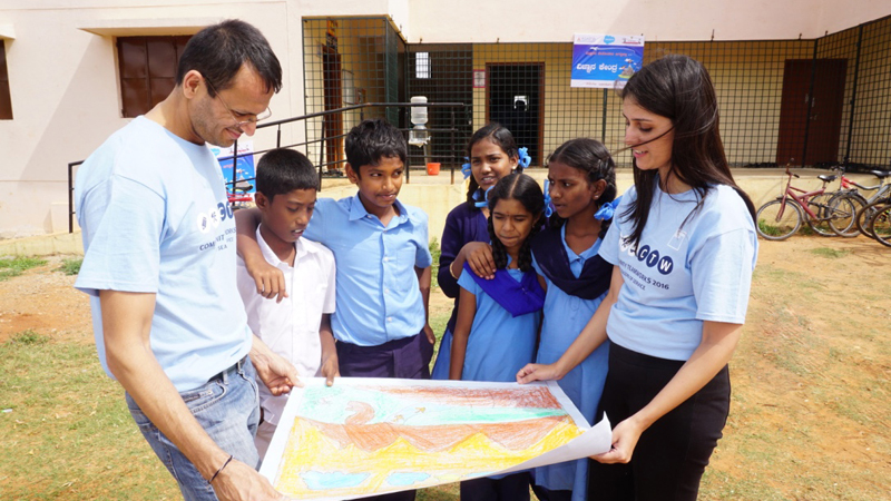 A few Goldman Sachs employees standing around some children and a drawing in Bangalore.