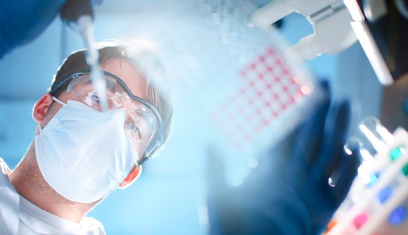 A scientist puts a solution into various vials. 