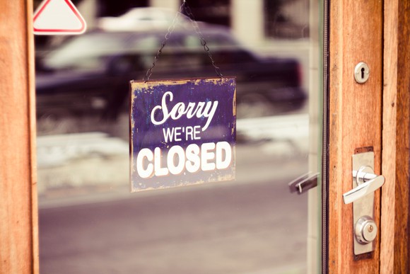 Picture of a sign on a door that says "Sorry, we're closed."