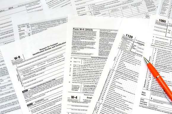 An assortment of tax forms, and a pen.