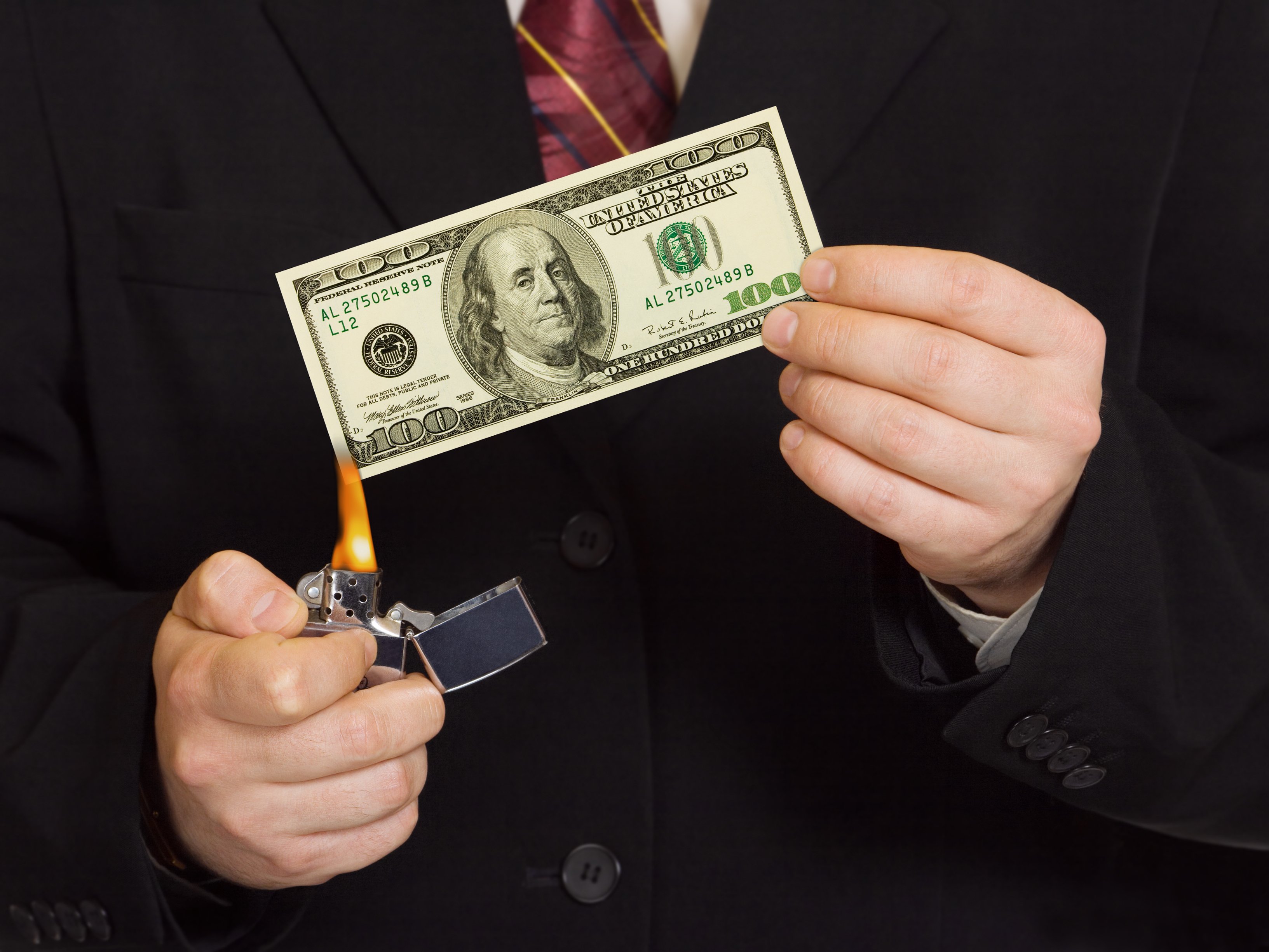 A businessman lights money on fire