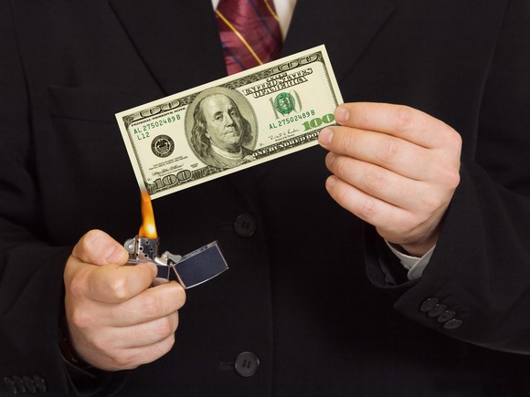 A businessman lights money on fire