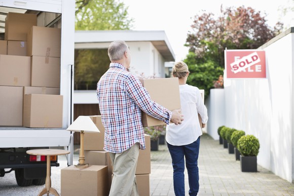 Older couple with moving van, carrying boxes