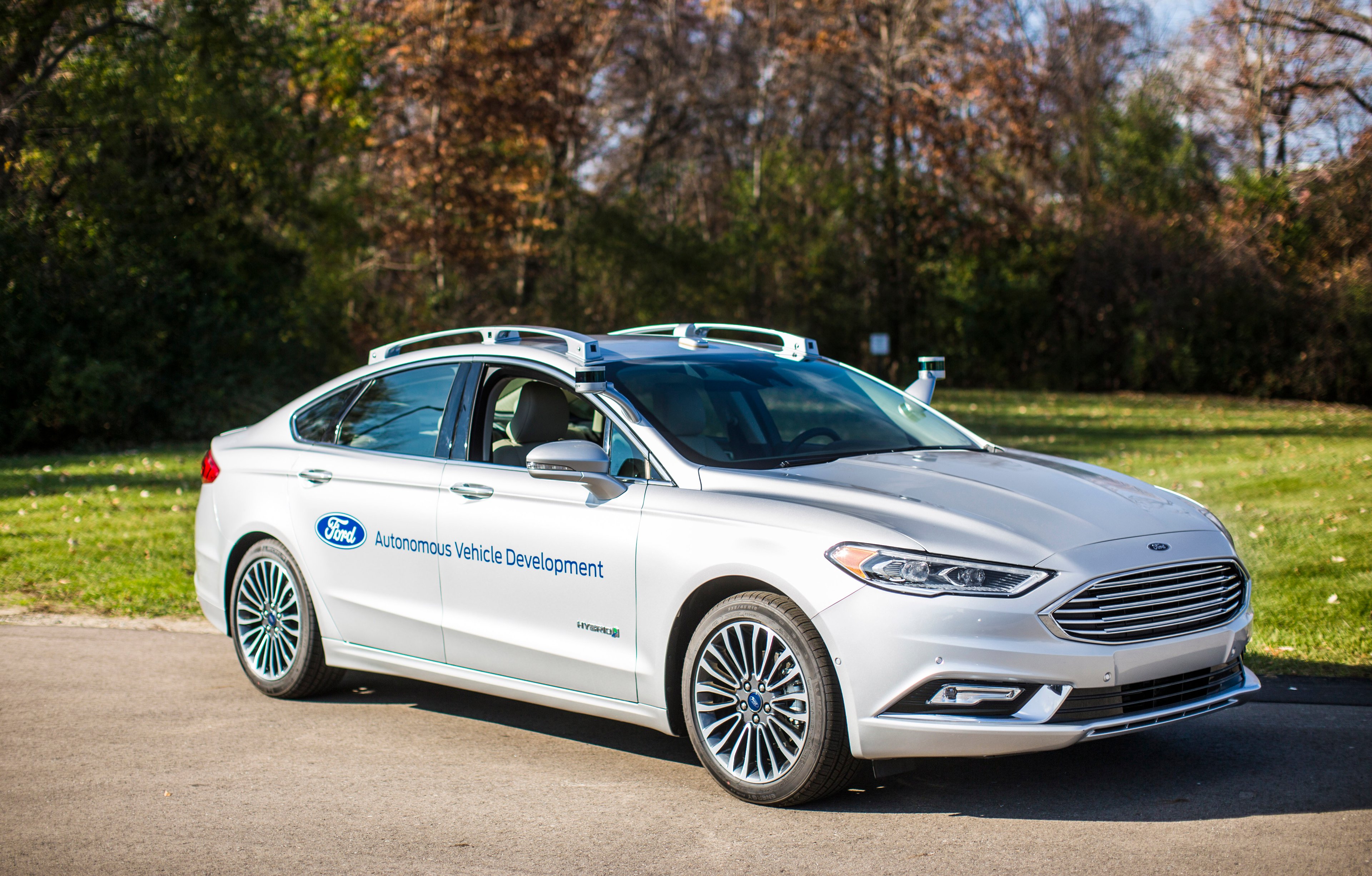 A Ford Fusion Hybrid sedan with visible self-driving sensor hardware. 