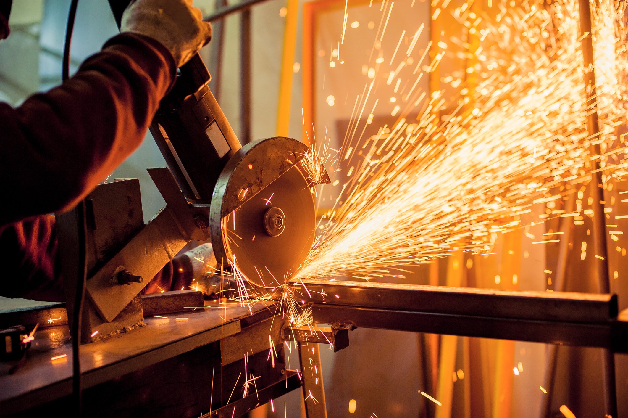 Sparks fly from a cutting tool in a manufacturing facility.