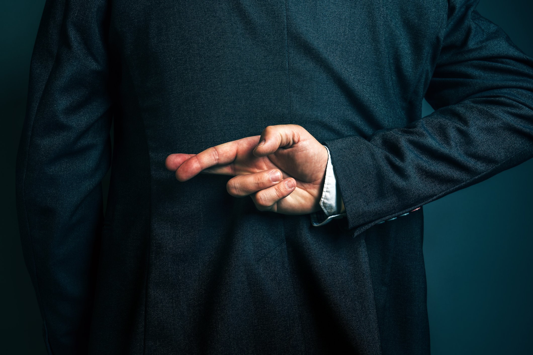 businessman with fingers crossed behind back