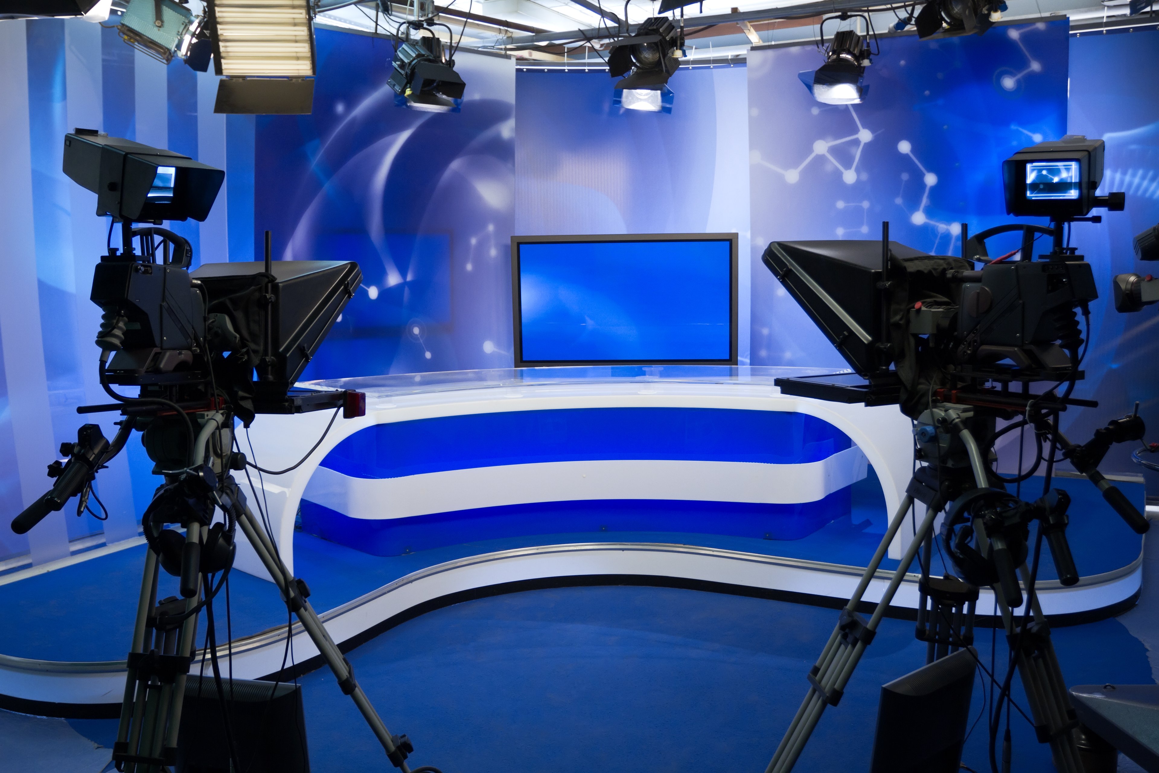 Two TV cameras point toward a stage in a news studio