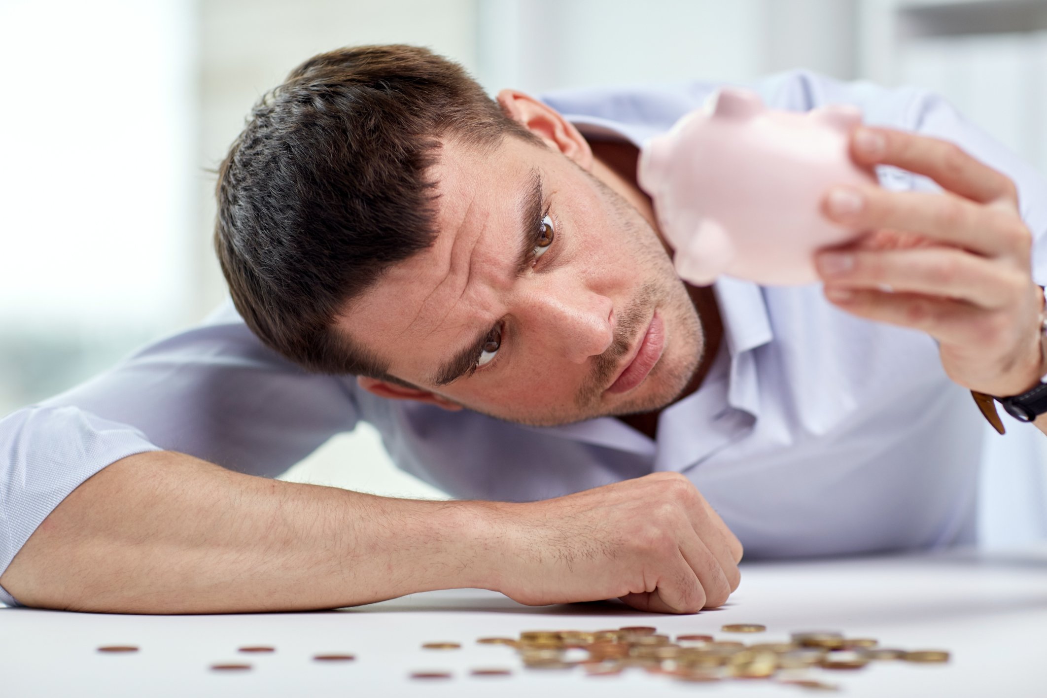 A man emptying his piggy bank and realizing there's very little saved. 