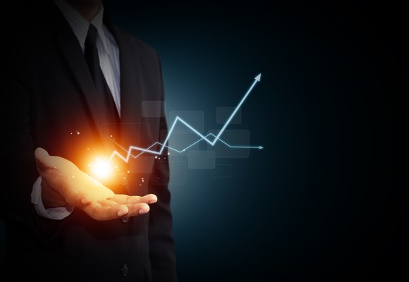 A man in a suit holds his palm out; above it hovers a ball of light, from which emanates a rising arrow as in a stock chart.