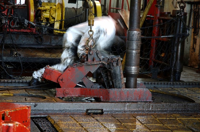 Roughneck setting drill pipe on a rig platform.