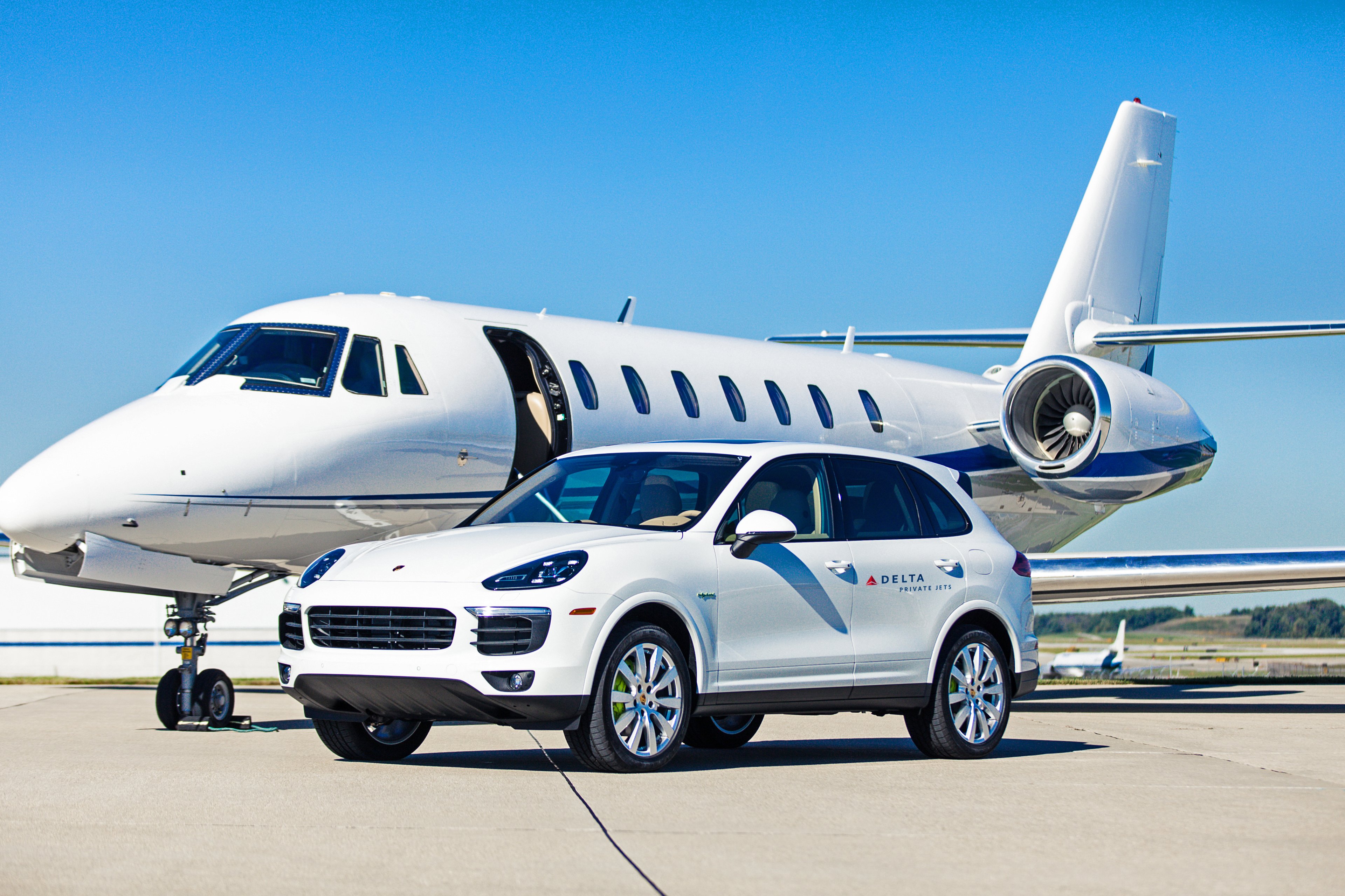 A private jet is behind a Porsche SUV used by Delta Private Jets for transporting customers.