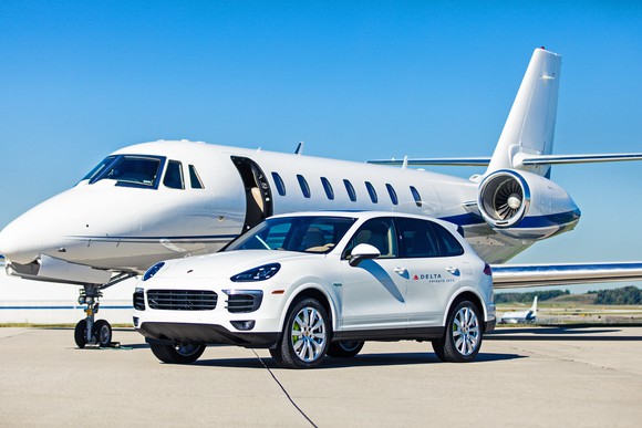 A private jet is behind a Porsche SUV used by Delta Private Jets for transporting customers.