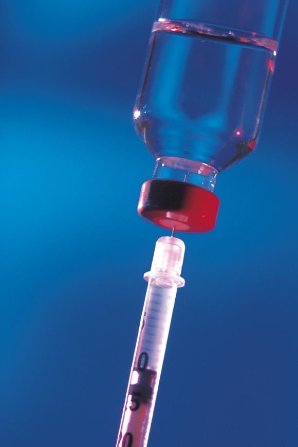 A syringe being filled from a vial