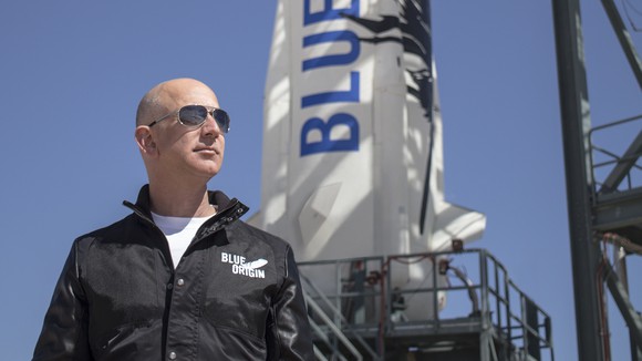 Jeff Bezos standing next to New Shepard rocket.