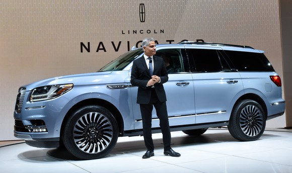 Galhotra stands in front of a light-blue Lincoln Navigator SUV.