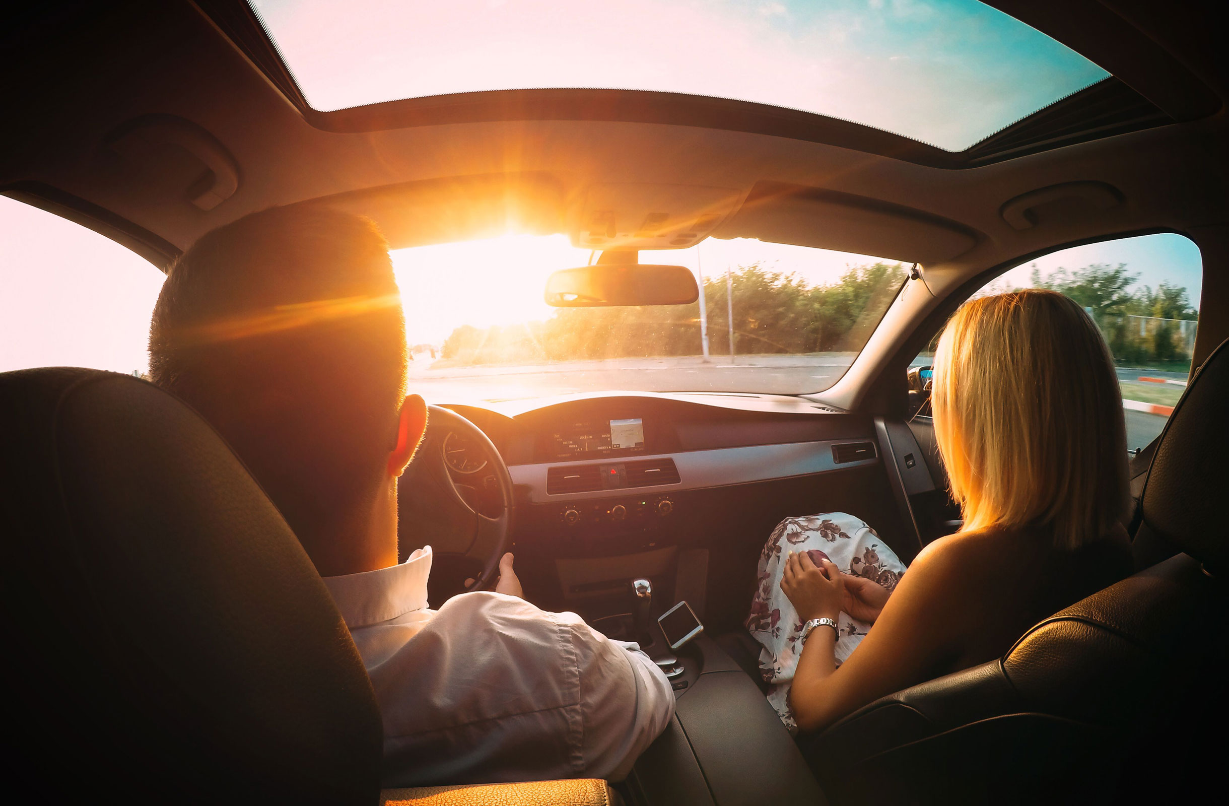 A man and a woman in a car at sunset.