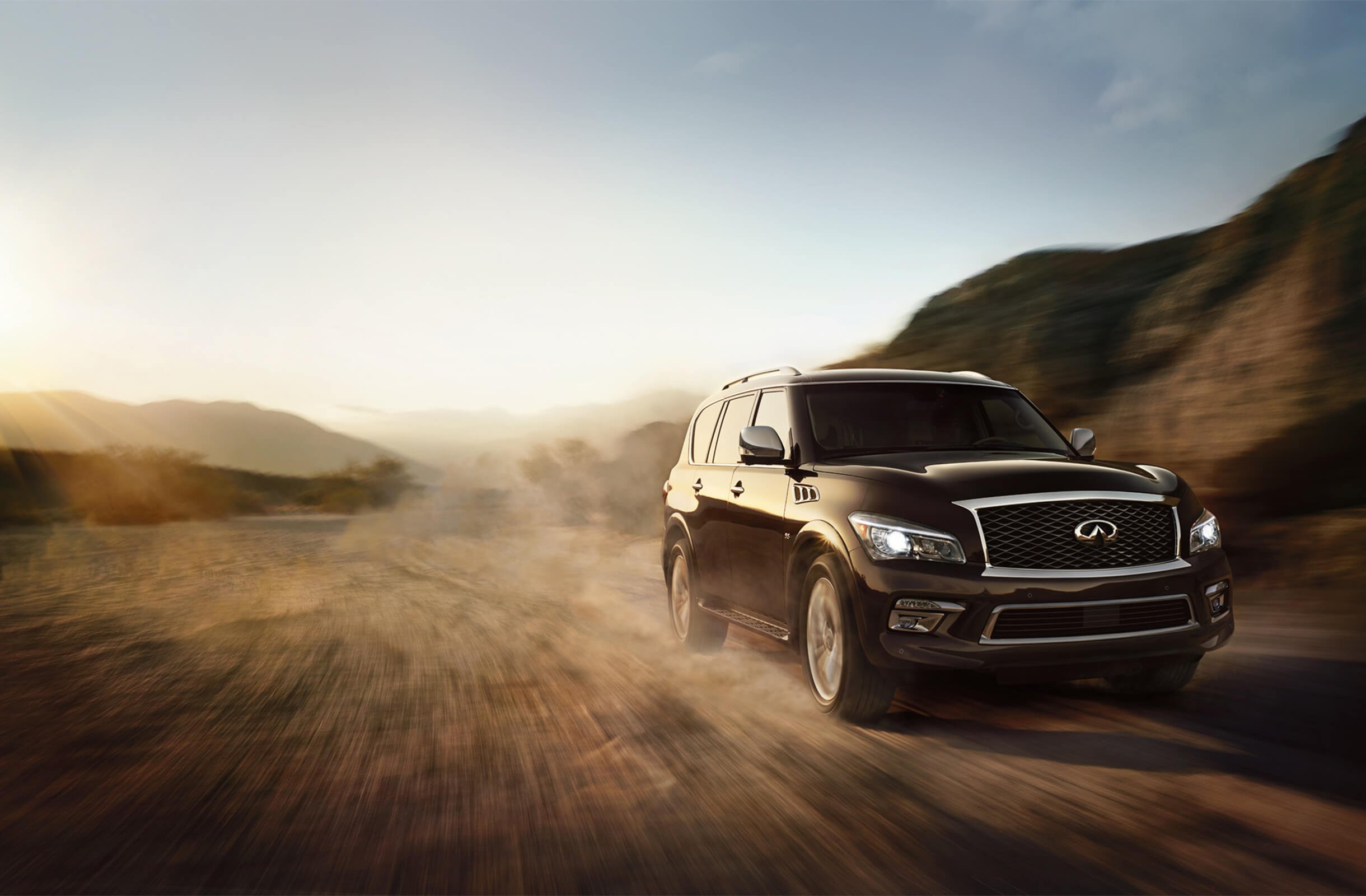A Nissan Infiniti SUV driving down a dirt road.