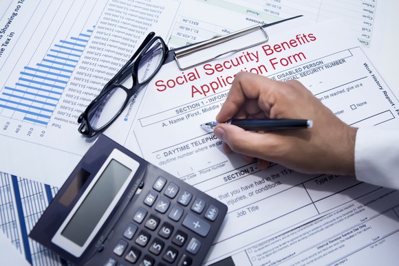 Hand filling out a Social Security benefits application form.