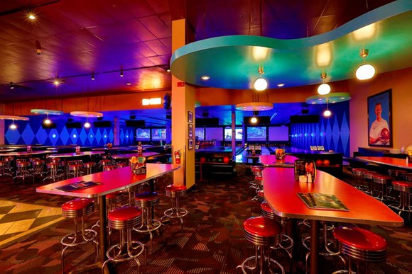 The billiards pool area of a Dave and Buster's. Red tables and chairs are set up for guests to eat while playing.