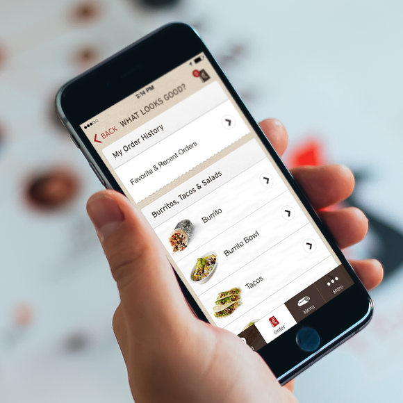 A hand holding a smartphone with the Chipotle app open. 
