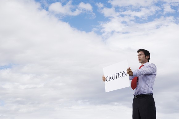 businessman holding a sign that says "caution"