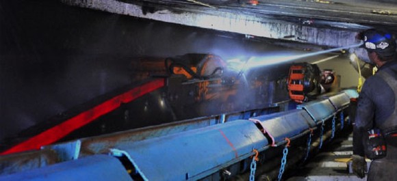 worker inspecting underground coal mining equipment