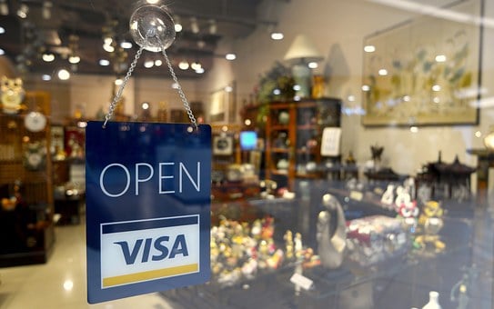 Sign hanging in store window displaying Visa card and saying "Open"