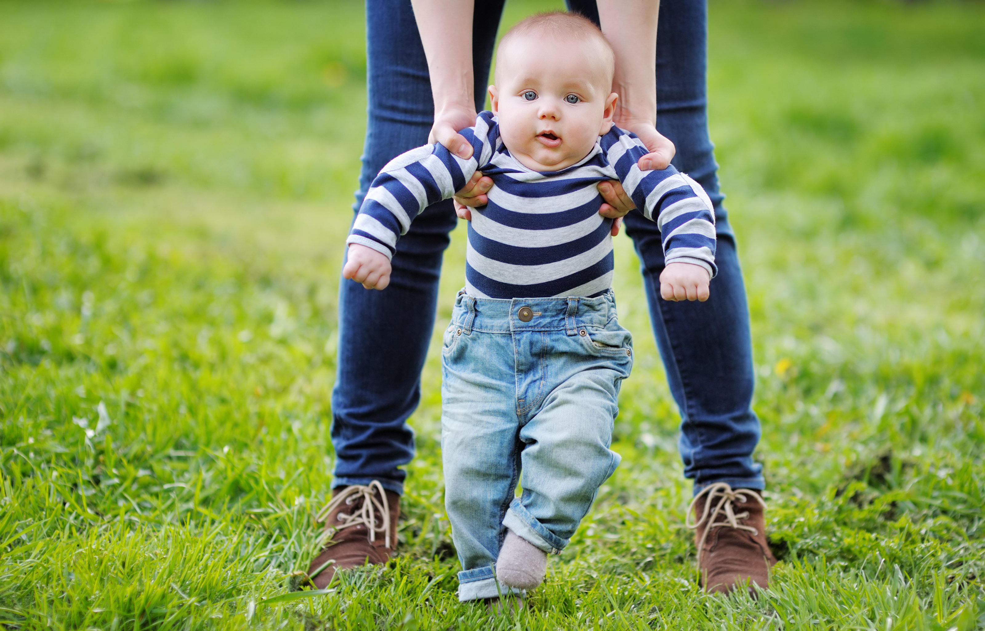 Picture of a woman helping a baby stand up.