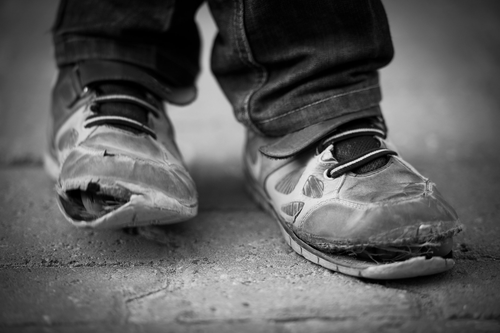 A black and white photo of a child's worn down shoes.