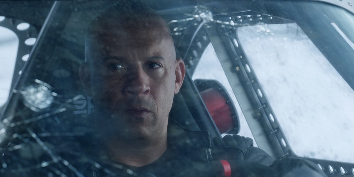 Actor Vin Diesel as "Dom" in "Fate of the Furious" driving a car with a cracked windshield.