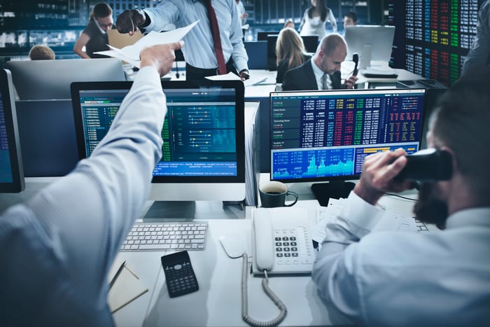 Several traders look at stocks on their computer terminals