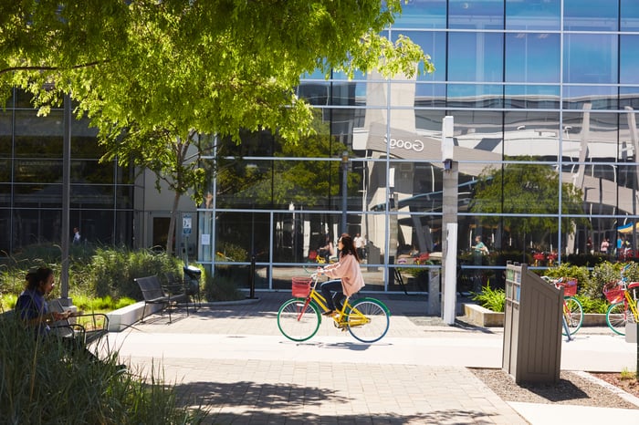 A person riding a bike in front of the Google campus. 