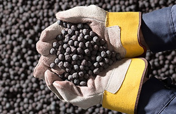 A miner holds a pile of iron ore pellets in his hands.