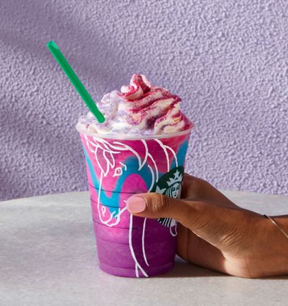A hand holding a Unicorn Frappuccino