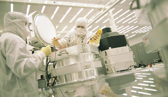 Two people working on semiconductor equipment.