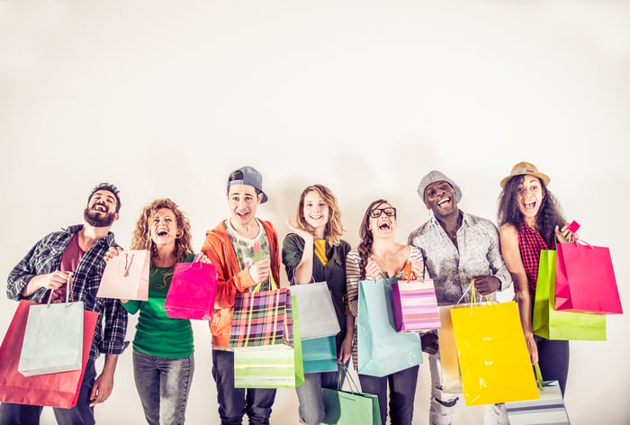 Several Millennials smiling while holding shopping bags.