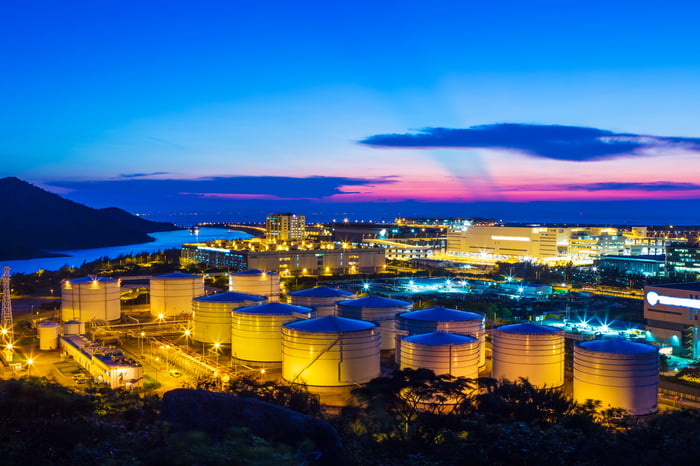 Oil refinery storage tanks at sunset