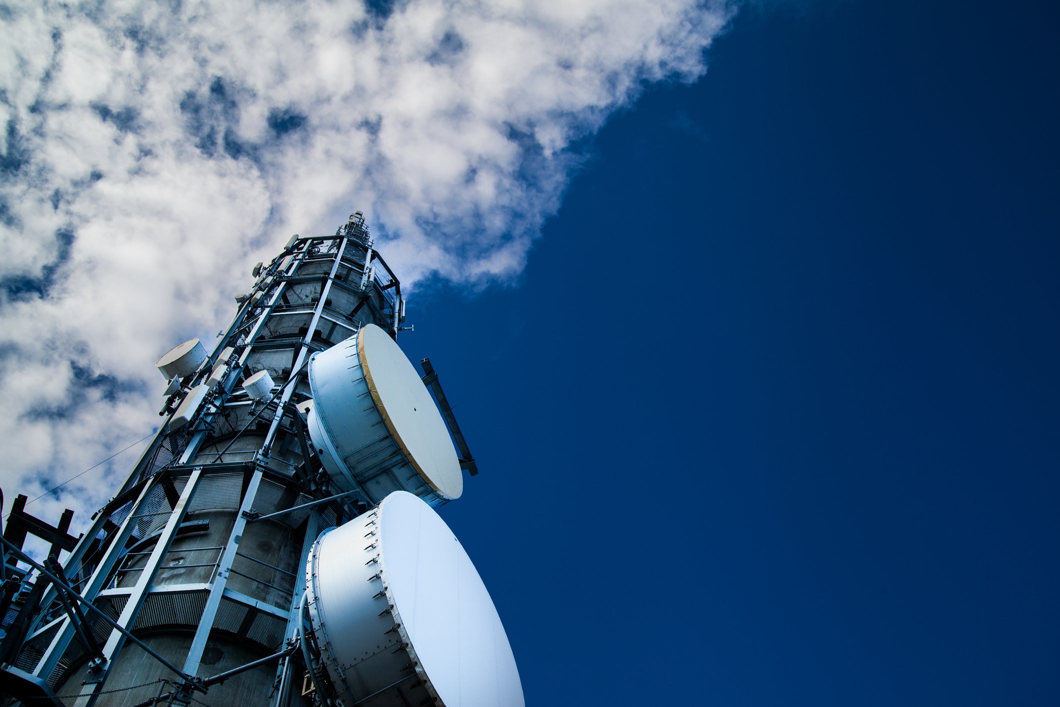 Looking up at a cell tower and into the sky.