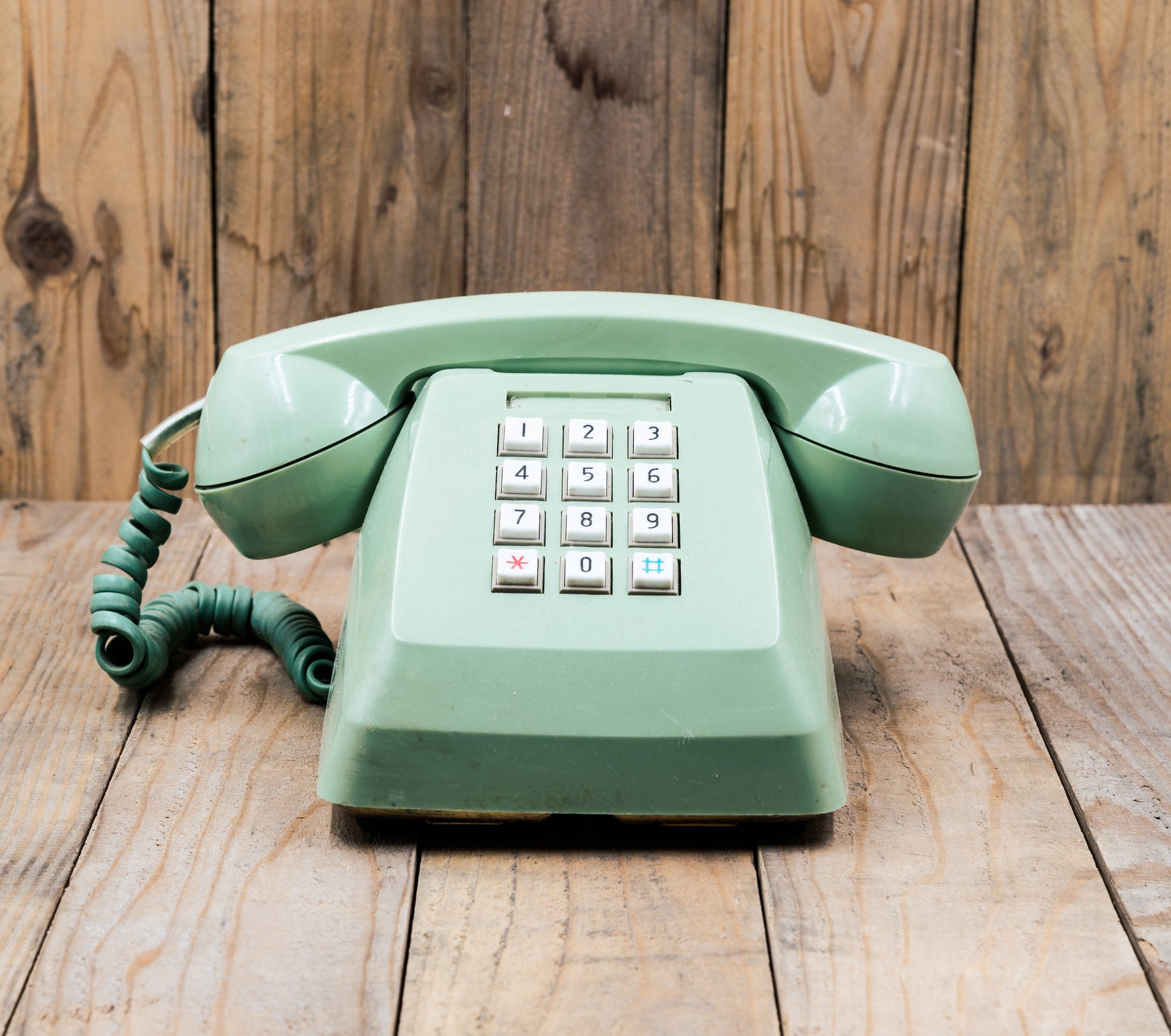 An old-fashioned green telephone rests on a table.