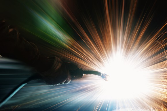 A hand welding with dramatic sparks around