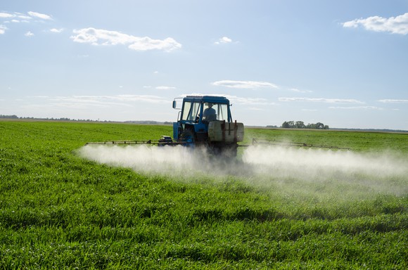 Tractor spraying pesticide chemicals on a field of crops