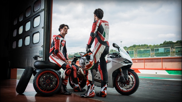 Two motorcyclists by a Ducati motorcycle