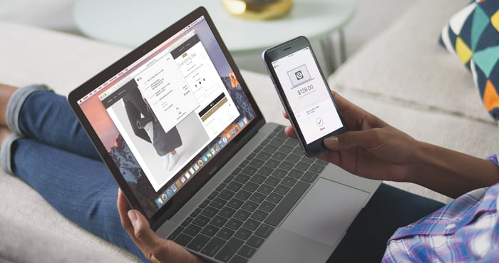 Person using Apple Pay on the Web with a MacBook and iPhone